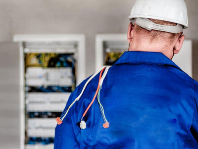 Electricista con casco trabajando en un tablero eléctrico